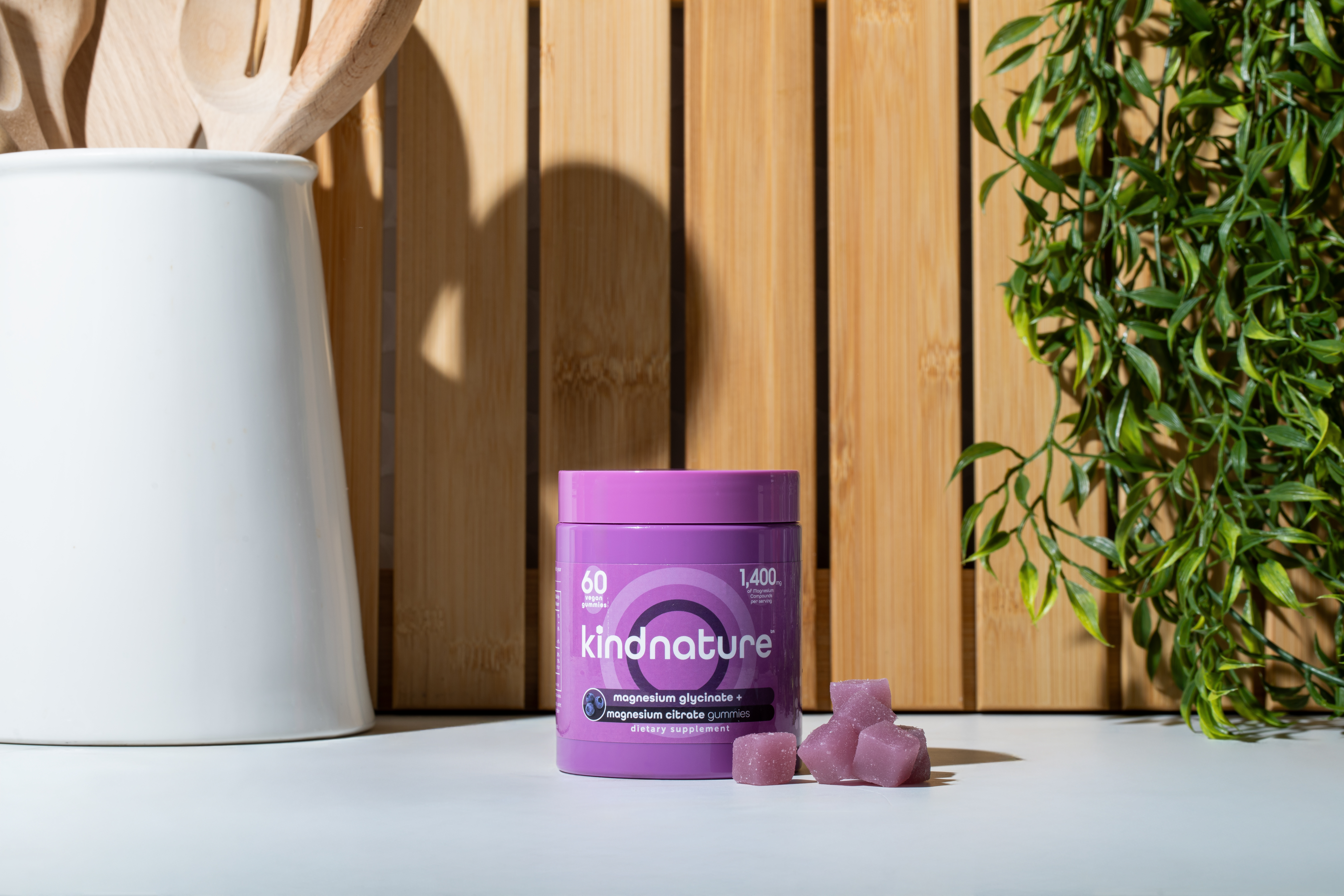 KINDNATURE Magnesium Glycinate Citrate gummies bottle on a wooden surface with purple gummies displayed